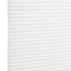 White pleated cellular window shade, fully lowered and closed with regular horizontal honeycomb cells; filtering diffuse light in a bright, minimal interior setting.