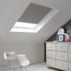 Room with white eaves wall, dark blue-grey wall to right with a shabby chic white drawer unit, a contemporary white chair, white painted floorboards and a skylight blind in pale slate grey.