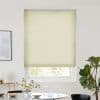 Light-yellow pleated cellular shade, fully lowered over a sash window, filtering daylight; set in a bright minimalist dining area with round table and vase, framed art left, fiddle‑leaf fig right.