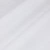 Sheer white curtain panel with fine woven texture, draping in soft diagonal folds, gently filtering diffuse light against a bright, neutral interior—close-up view.
