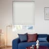 White cellular (honeycomb) blind lowered over the window, pleated horizontal cells with a slightly raised bottom edge; filtering soft daylight into a modern living room with a navy sofa, cushions, and lamp.