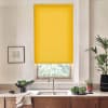Yellow roller blind covers upper window, leaving a narrow view of greenery; a kitchen sink and faucet sit below on a marble countertop with wooden cabinets, potted plants, and bowls of produce.