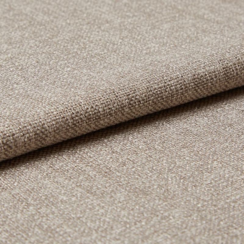 Beige woven upholstery fabric (tight basket weave), folded over an edge, displaying textured threads and slight sheen; close-up on a flat surface under soft, diffused lighting.