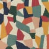 Abstract patchwork of irregular multicolored shapes forms a mosaic across a textured fabric surface, using muted teal, navy, mustard, coral, green, and cream tones.