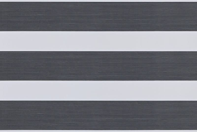 Dual-layer horizontal zebra roller blind mounted across the frame, aligned into alternating wide opaque white bands and narrow ribbed dark-gray slats, partially filtering light; interior close-up with soft even lighting.