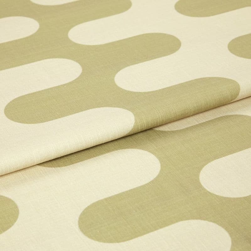 Fabric with large olive‑green rounded geometric motifs, folded and layered, showing woven texture and seams; studio‑lit close-up of a neutral‑colored textile sample.