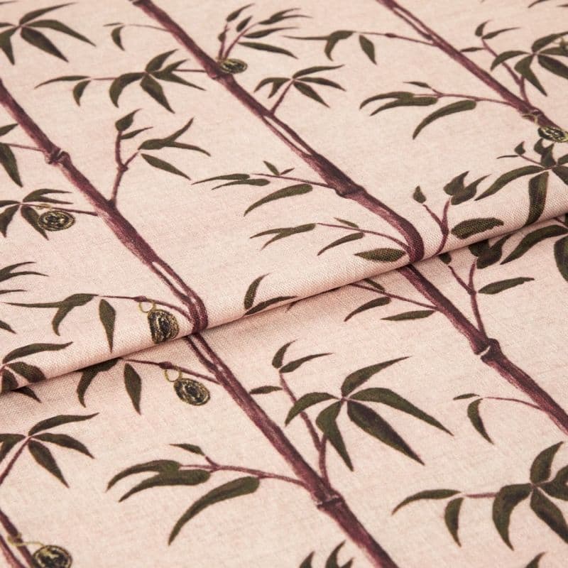 Folded fabric sample in blush pink background with linear print of bamboo shoots and leaves.