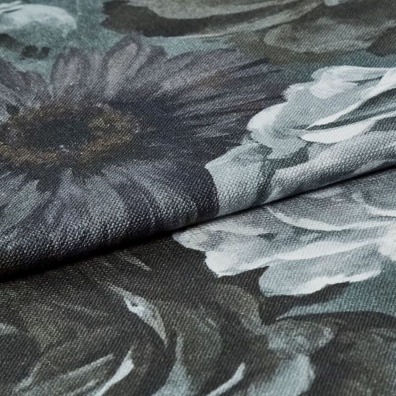 Dark floral upholstery fabric folded across the frame, coarse woven texture and oversized gray-white flower prints visible; fabric layered on itself under soft, even lighting in a close-up studio-style view.