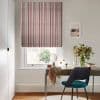 A striped Roman blind, lowered over the window with red, navy and cream vertical bands, filtering soft daylight; a home office desk with teal chair and vase of flowers.