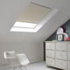 Room with white eaves wall, dark blue-grey wall to right with a shabby chic white drawer unit, a contemporary white chair, white painted floorboards and a skylight blind in pale mushroom.