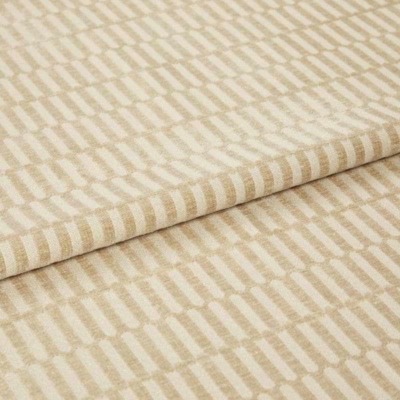Textured beige-and-cream fabric with raised rectangular stripe pattern, folded once and layered, shown close-up on a neutral surface under soft, even studio lighting.