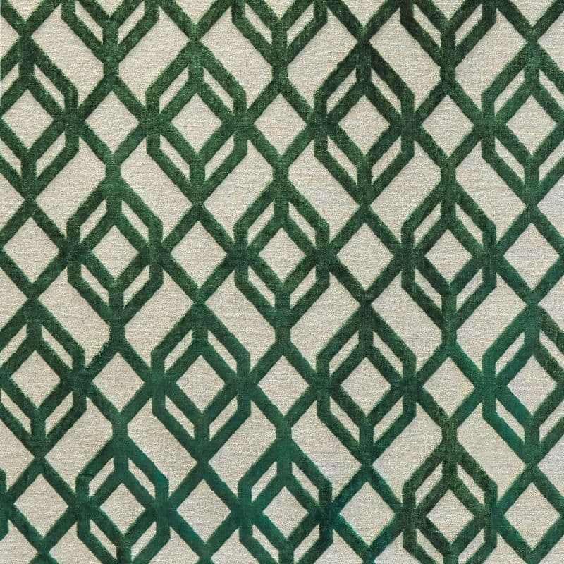 Beige rug with raised dark‑green geometric diamond lattice pattern, repeating across the surface; the rug lies flat, covering a floor‑like surface in soft, even indoor lighting.