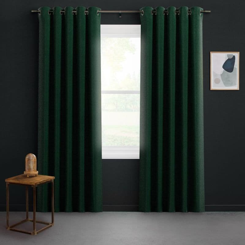 Dark green grommet-top curtains hang on a metal rod, parted to reveal bright daylight through the window; set against dark walls with a wooden side table and abstract framed art.