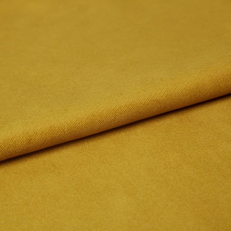 Mustard-yellow fabric, folded once with a visible textured edge, lying flat; soft pile catching even studio lighting, close-up composition emphasizing a smooth, plush surface.