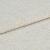 Beige woven fabric folded once, overlapping to show its edge; coarse boucle-like weave texture visible; close-up, even studio lighting on a neutral surface.