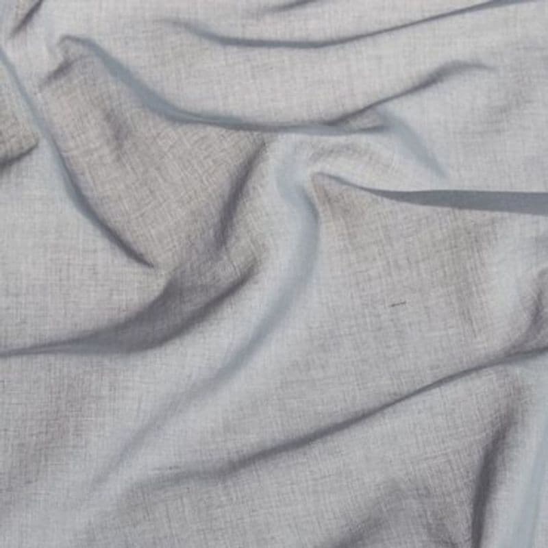 Light-gray woven fabric (linen-like) draped and rumpled into soft folds and creases, lying across a flat surface in diffuse indoor light, showing visible weave texture and subtle shadows.